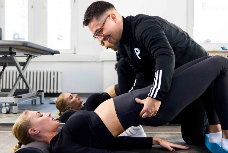 Physiotherapeut unterstützt Patientin bei Beinübung im Rehasport-Training in Neuss